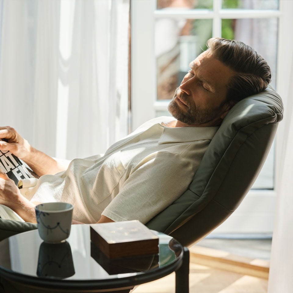 A man relaxing in a Stressless Mayfair leather recliner by a window